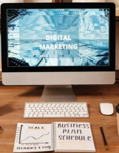 Basic Digital Marketing Concept blog images shows A laptop and a book on a table both are open and shows text written in tha